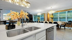 Een moderne keuken met een dubbele spoelbak, roestvrijstalen apparatuur en een eethoek met een groot raam.