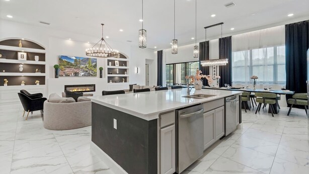 A modern kitchen with a large island, built-in shelving, and pendant lighting. - Regal 15BR 16.5BA, Sleeps 40, Lake View, Theater (Kissimmee)