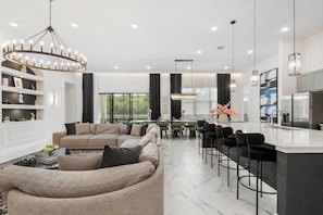 Ein modernes Wohnzimmer mit Sofa, Essbereich und Küche.
