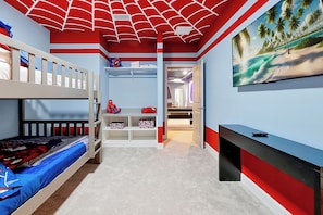 Ein Kinderzimmer mit Etagenbetten, einem Schreibtisch und einem Fernseher.