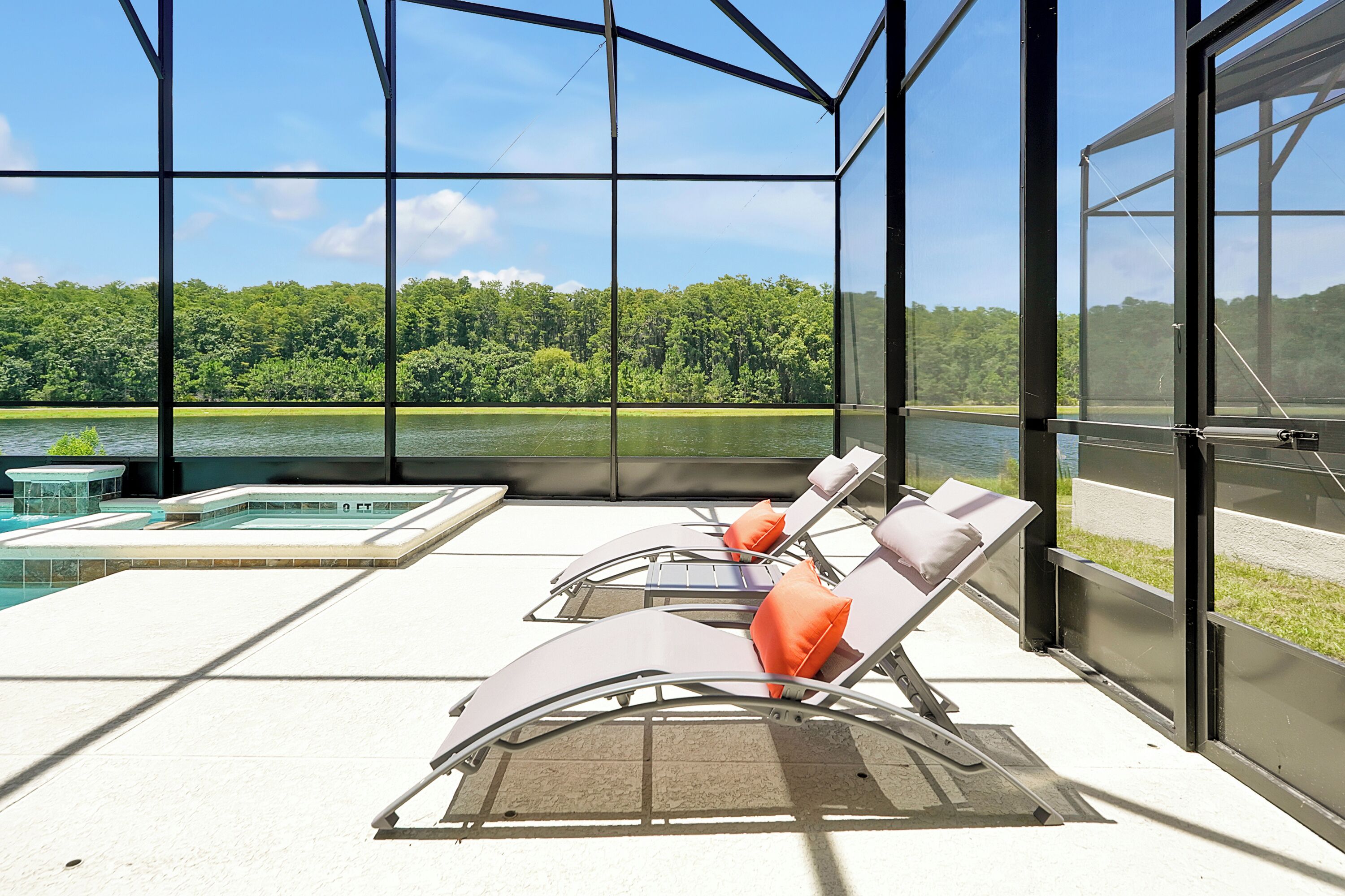 Un espace de détente extérieur, baigné de soleil, avec une piscine, des chaises longues et une vue sur un lac et une forêt.