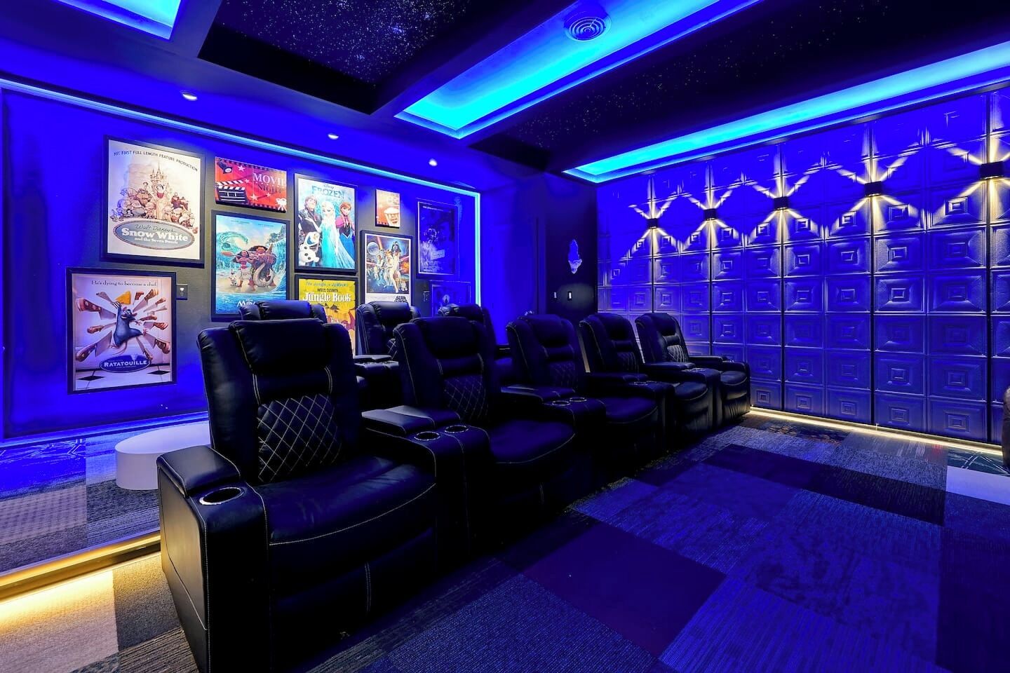 A cinema room with multiple reclining seats, a wall with movie posters, and a patterned wall design.