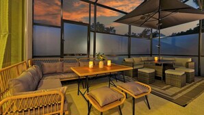 A covered outdoor seating area with wicker furniture, a table, and a large umbrella. - Stunning 12BR 11.5BA, Sleeps 27, Theater, Game Rm (Kissimmee)