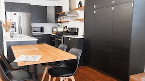Eine moderne Küche mit dunklen Schränken, einem Holztisch und schwarzen Stühlen.