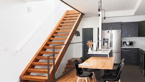 Eine moderne Küche mit einer Holztreppe, einem Essbereich mit Tisch und Stühlen und einer kleinen Sitzecke.