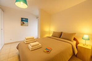 Ein Hotelzimmer mit einem Bett, einem Nachttisch, einer Lampe, einem Gemälde und Handtüchern.