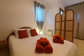 Ein Hotelzimmer mit einem Bett, Kissen, einem Nachttisch, einer Lampe und einem Fenster mit Vorhängen.