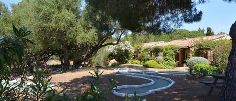 Un jardín con una fuente sinuosa, rodeado de árboles y arbustos.