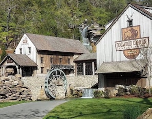 A rustic building with a large water wheel, a waterfall, and a sign reading 'Dogwood Canyon Nature Park.'