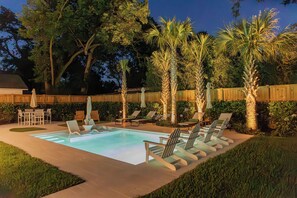 A backyard with a swimming pool, lounge chairs, and palm trees. - New! Cottage with pool near pier village! (St Simons Island)