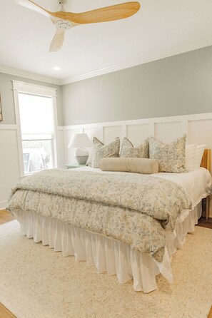 A bedroom with a bed, a ceiling fan, a nightstand, and a window. - New! Cottage with pool near pier village! (St Simons Island)