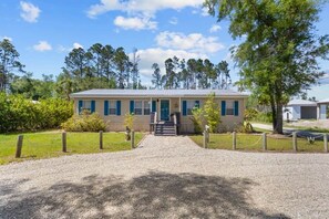 A single-story building with a front entrance, a gravel driveway, and a chain-link fence. - Hatchee Haven - Home in Steinhatchee (Steinhatchee)