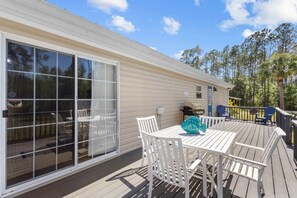 A covered deck with white furniture and a glass door leading to an outdoor area. - Hatchee Haven - Home in Steinhatchee (Steinhatchee)