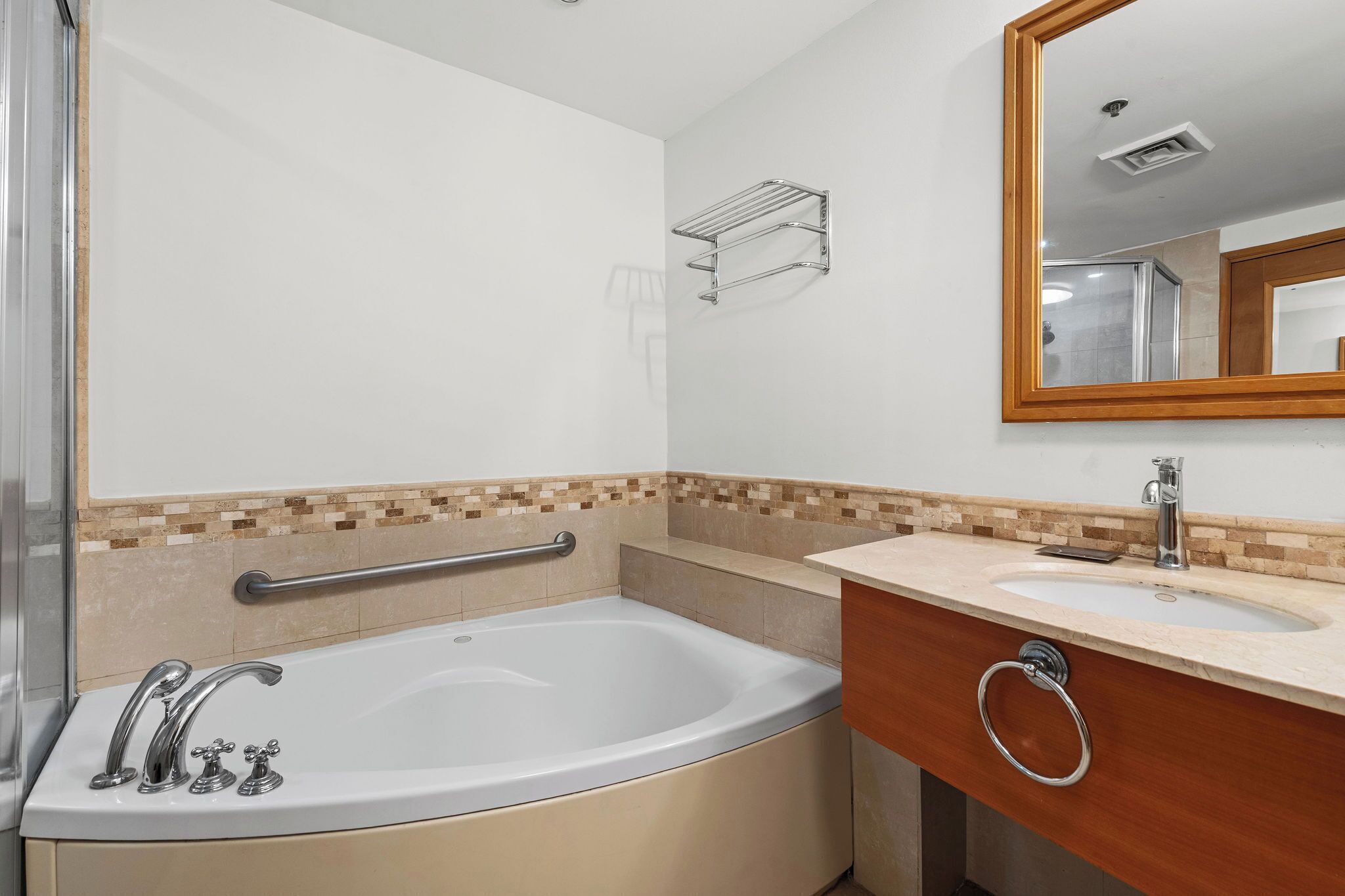 A bathroom with a bathtub, a sink, a mirror, and a towel rack.