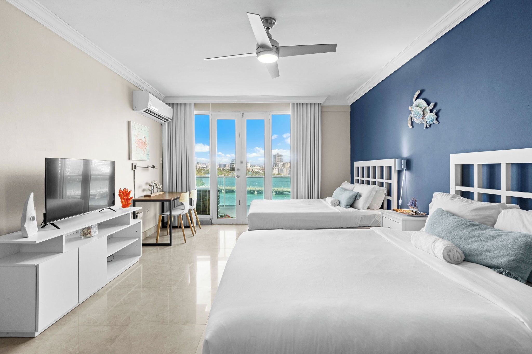 Habitación de hotel moderna con cama, televisión, escritorio y vista al océano.