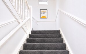 Eine Treppe mit einem gerahmten Schild, auf dem 'HELLO Sunshine' steht, und einem Fenster am oberen Ende.