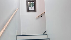 A staircase with white steps and blue edges, a wooden handrail on the left, and a framed clover on the wall.