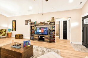 Ein Wohnzimmer mit Fernseher, Bücherregalen, einem Couchtisch und einer Tür.