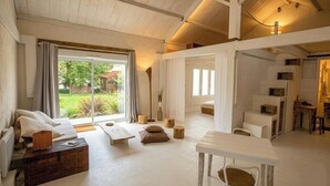 Um quarto espaçoso com uma janela grande, teto de madeira e um espaço para refeições.