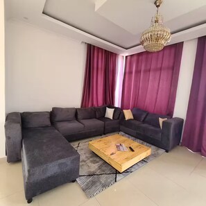 Ein modernes Wohnzimmer mit einem Ecksofa, einem Holztisch und einer Chandelier.