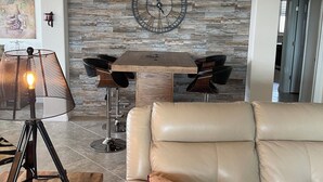 A living room with a stone fireplace, leather sofa, and a table lamp. - SARASOTA NATIONAL - SEASONAL RENTAL -WITH GOLF MEMBERSHIP FOR 2 - 3 BR/2 BATH (Venice)
