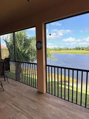 A covered outdoor area with a view of a body of water, a clock, and a chair. - SARASOTA NATIONAL - SEASONAL RENTAL -WITH GOLF MEMBERSHIP FOR 2 - 3 BR/2 BATH (Venice)