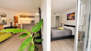 A modern apartment with a kitchen, dining area, and a bedroom with a bed and a window. - Furnished Waikiki 1BR • Pet-Friendly • Utilities Included • Walk to Beach (Honolulu)