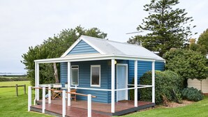 A small blue house with a porch, a table, and chairs.