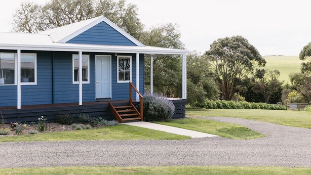A blue house with a porch, a front door, and a staircase leading to the entrance. - Suma Park Estate (Marcus Hill)