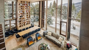 Ein geräumiges Zimmer mit großem Fenster, einer Holzbücherregal, einem Essbereich und einer gemütlichen Sitzecke.