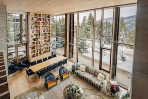 Ein geräumiges Zimmer mit großem Fenster, einer Holzbücherregal, einem Essbereich und einer gemütlichen Sitzecke.