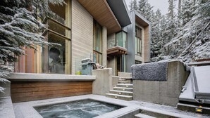 Ein modernes Gebäude mit großen Fenstern, einem Whirlpool und einer Treppe, die zum Eingang führt.