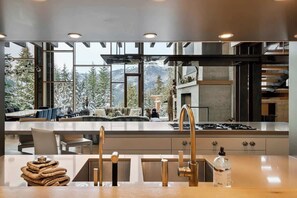 Eine moderne Küche mit einer großen Kochinsel, Edelstahlgeräten und Blick auf schneebedeckte Berge.