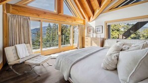 Una camera da letto con un letto grande, una chaise longue e vista sull'esterno.