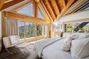 Ein Schlafzimmer mit einem großen Bett, einer Liege und Blick ins Freie.