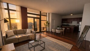 Ein geräumiges Wohnzimmer mit einer Couch, einem Couchtisch und großen Fenstern mit Blick auf die Stadt.