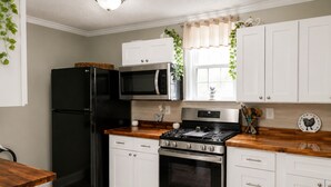 A kitchen with white cabinets, a black refrigerator, a microwave, a stove, and a sink.