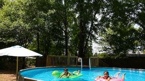 An outdoor swimming pool with a wooden deck and a fence.
