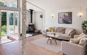 A modern living room with a fireplace, a sofa, a coffee table, and a painting on the wall. - 3 bedroom beautiful home in Gilleleje (Gilleleje)