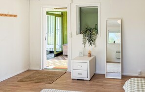 A bedroom with a white dresser, a mirror, a hanging plant, and a view of a green door. - 3 bedroom beautiful home in Gilleleje (Gilleleje)