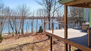 A wooden deck with a railing overlooking a body of water and trees.