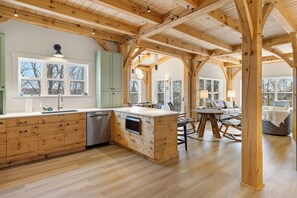 Eine geräumige Küche mit Holzschnitzereien, einer zentralen Kochinsel und einem Essbereich mit rundem Tisch und Stühlen.
