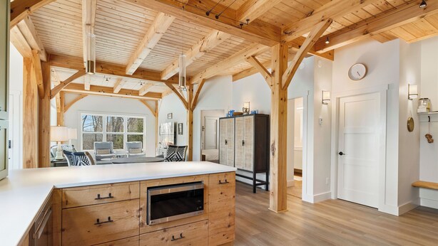 A spacious kitchen with wooden beams, a large island with drawers, and a view to the outside.