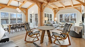 A spacious room with a wooden ceiling, a round table, and four rocking chairs.