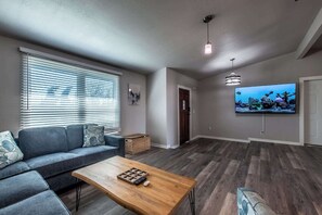 Ein Wohnzimmer mit einer Couch, einem Couchtisch, einem Fernseher und Holzböden.
