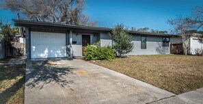 A single-story house with a garage, a front yard, and a small tree. - Hinman Haven + Hot tub (Corpus Christi)