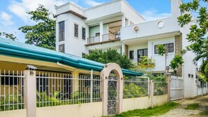 Una casa moderna de dos pisos con un porche cubierto, entrada protegida por un portón y un balcón.