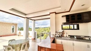 Cocina con barra, armarios blancos y vistas a zonas verdes.