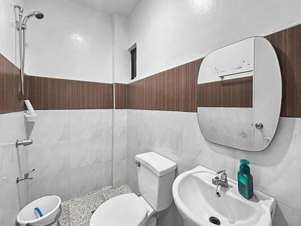 A bathroom with a toilet, bidet, sink, and mirror.