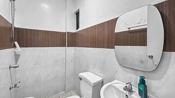 A bathroom with a toilet, bidet, sink, and mirror.